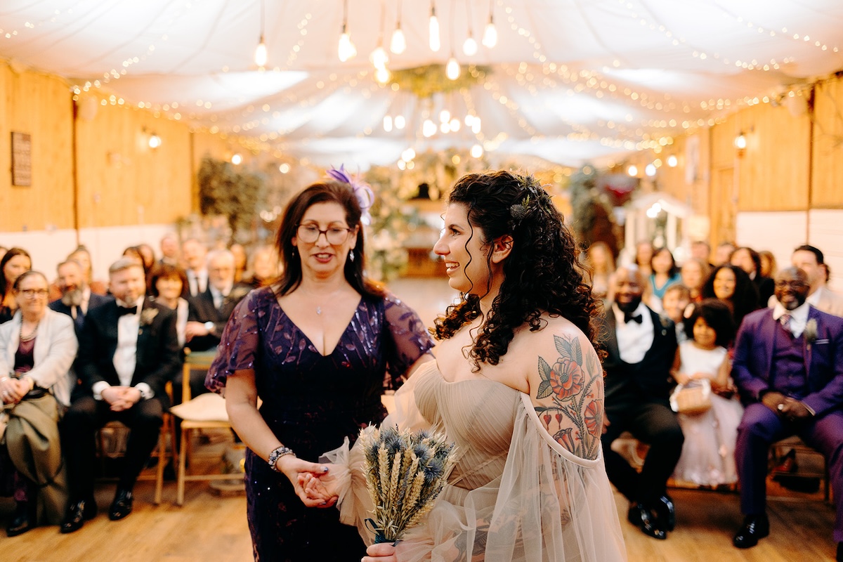 Bride walking down the aisle smiling during her February wedding ceremony at The Wellbeing Farm, captured with natural Wellbeing Farm wedding photography.