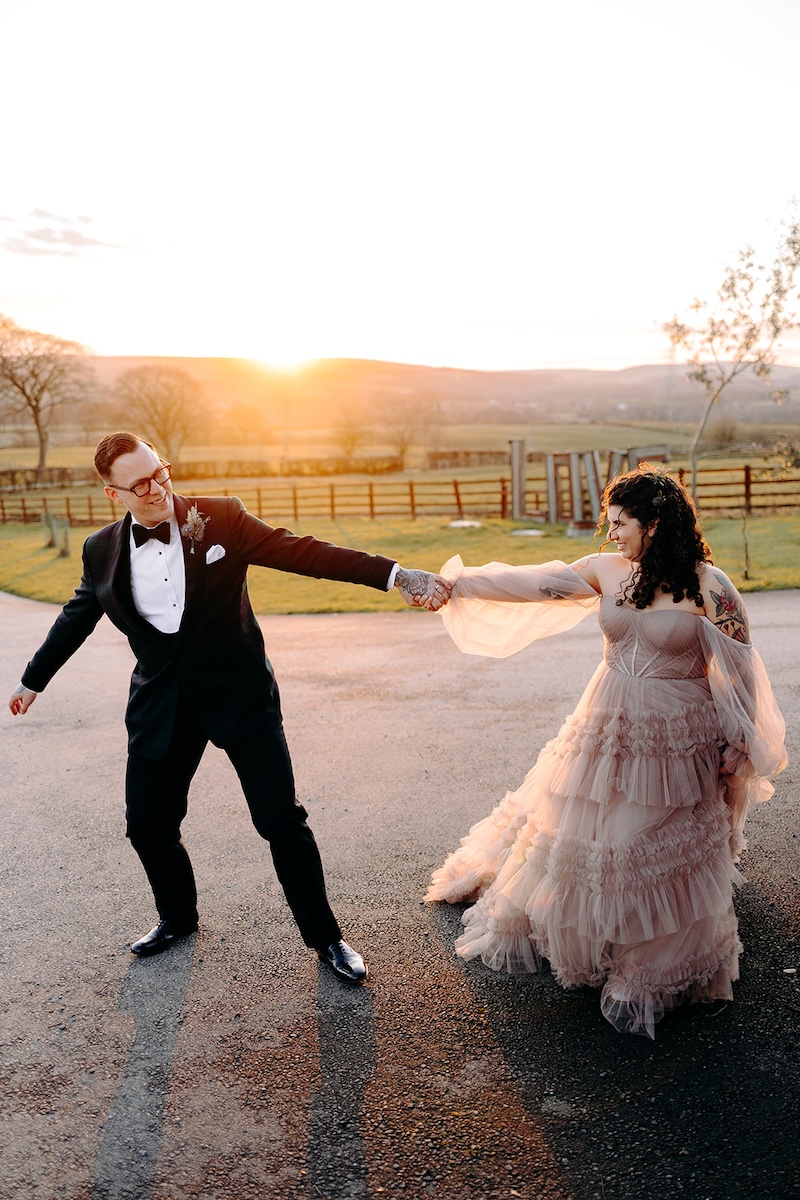 Bride and groom walking across the fields at sunset during golden hour portraits at The Wellbeing Farm, photographed by a wedding photographer.
