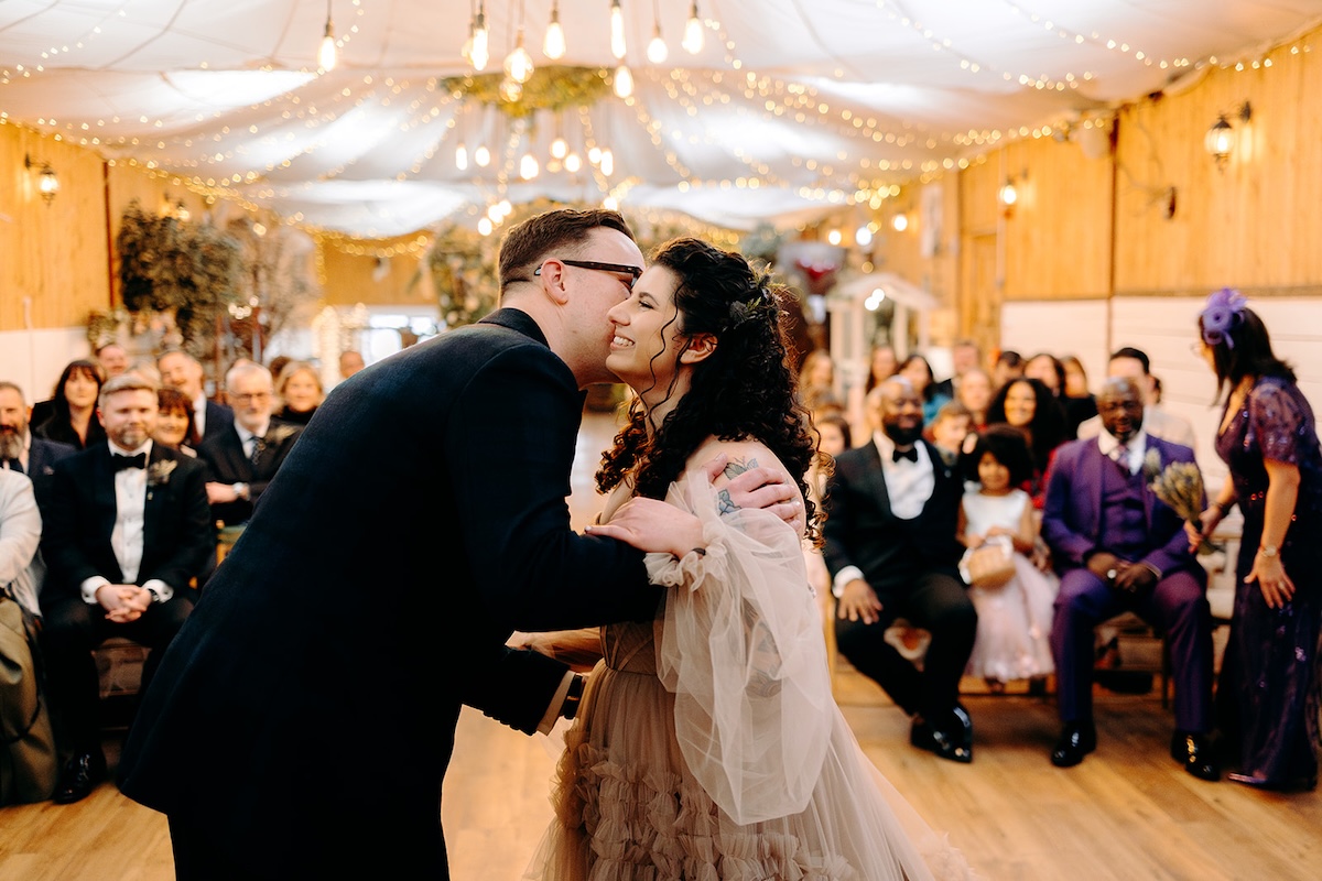Bride and groom meeting at the top of the aisle during the ceremony at The Wellbeing Farm, a joyful moment captured with documentary wedding photography.