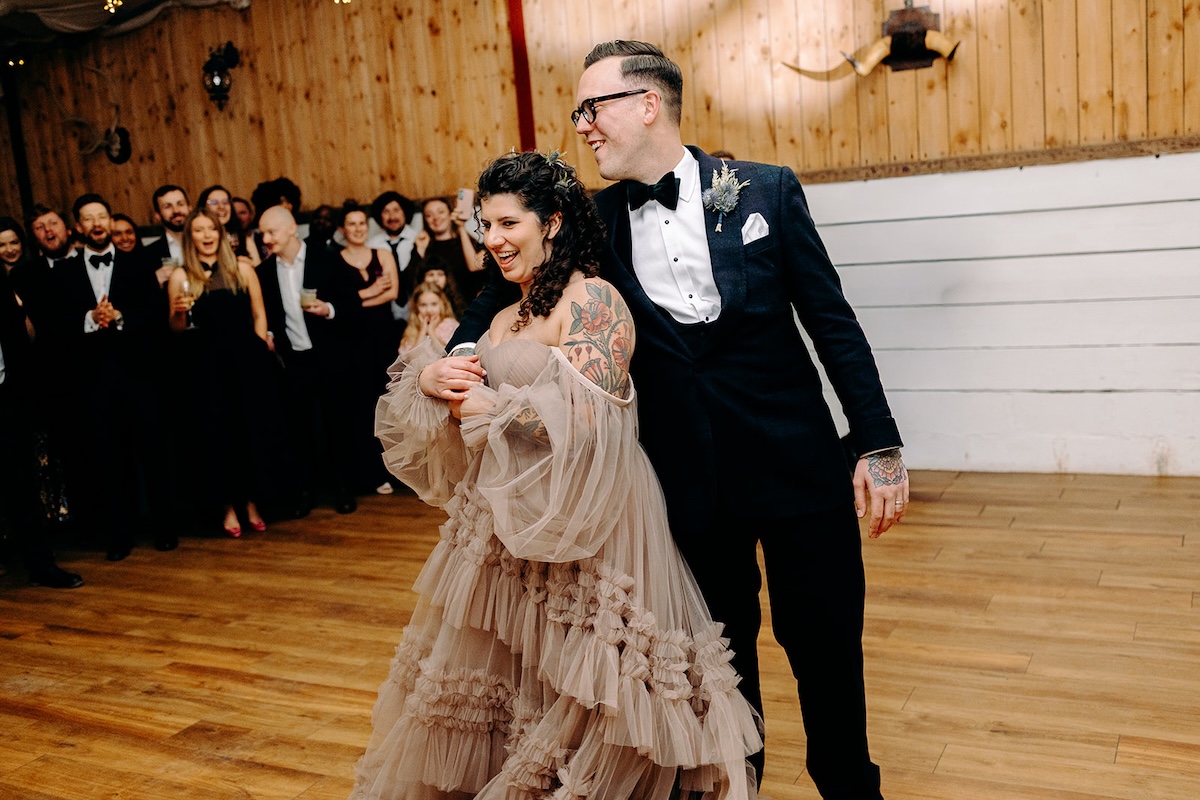 Bride and groom sharing their first dance together inside the barn reception at The Wellbeing Farm, photographed by their wedding photographer.