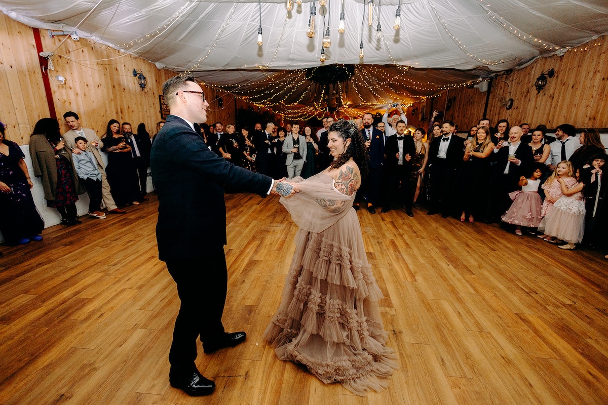 Bride and groom spinning during their first dance inside the rustic barn reception space.