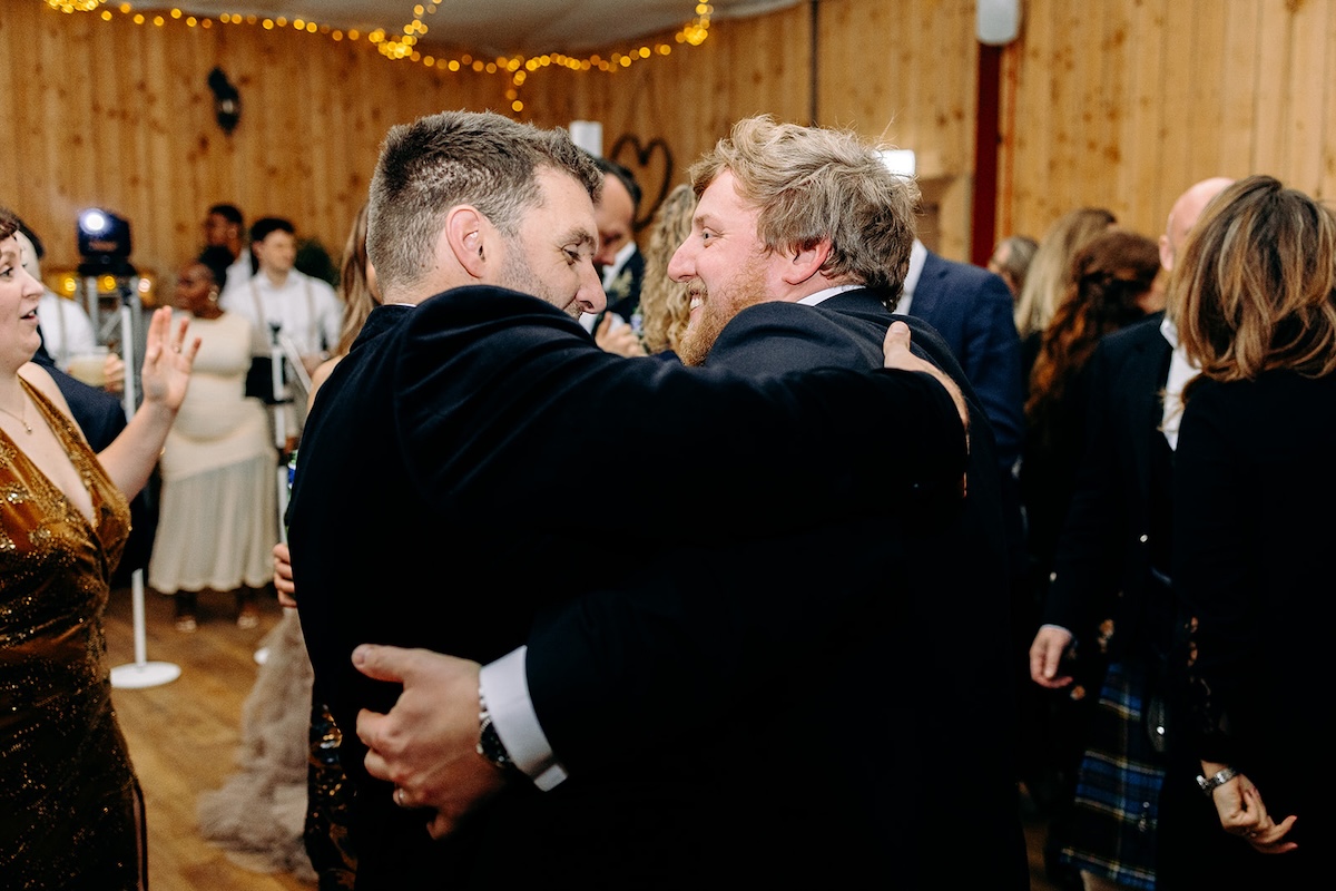Wedding guests hugging and celebrating together on the dancefloor at The Wellbeing Farm.