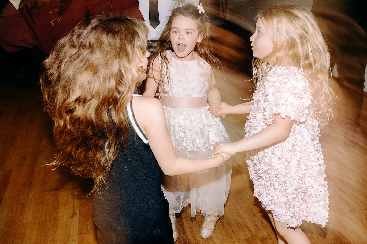 Young flower girl spinning on the dancefloor during the lively wedding party.