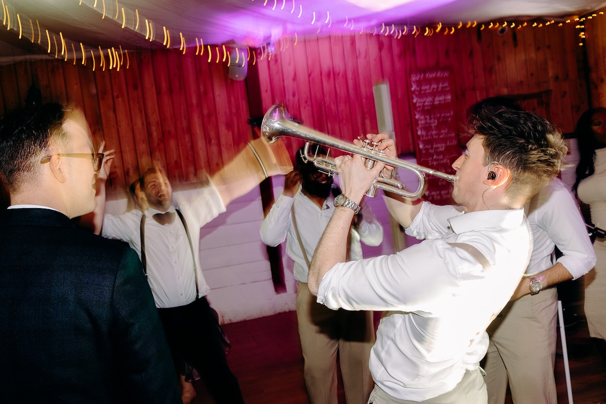Live band musicians playing trumpet during the wedding party at The Wellbeing Farm.
