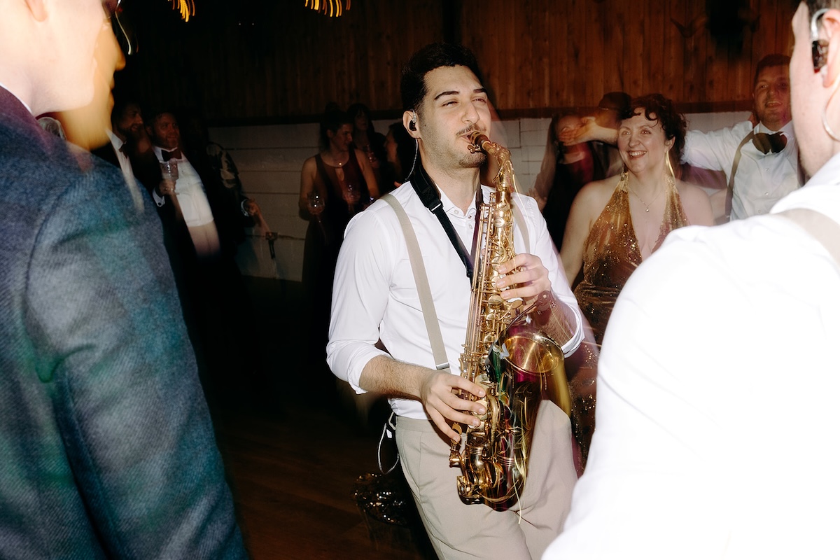 Saxophone player performing on the dancefloor surrounded by guests during the reception party.