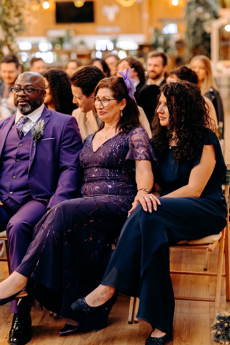 Wedding guests smiling and listening during the ceremony inside the rustic barn at The Wellbeing Farm, captured with natural wedding photography.