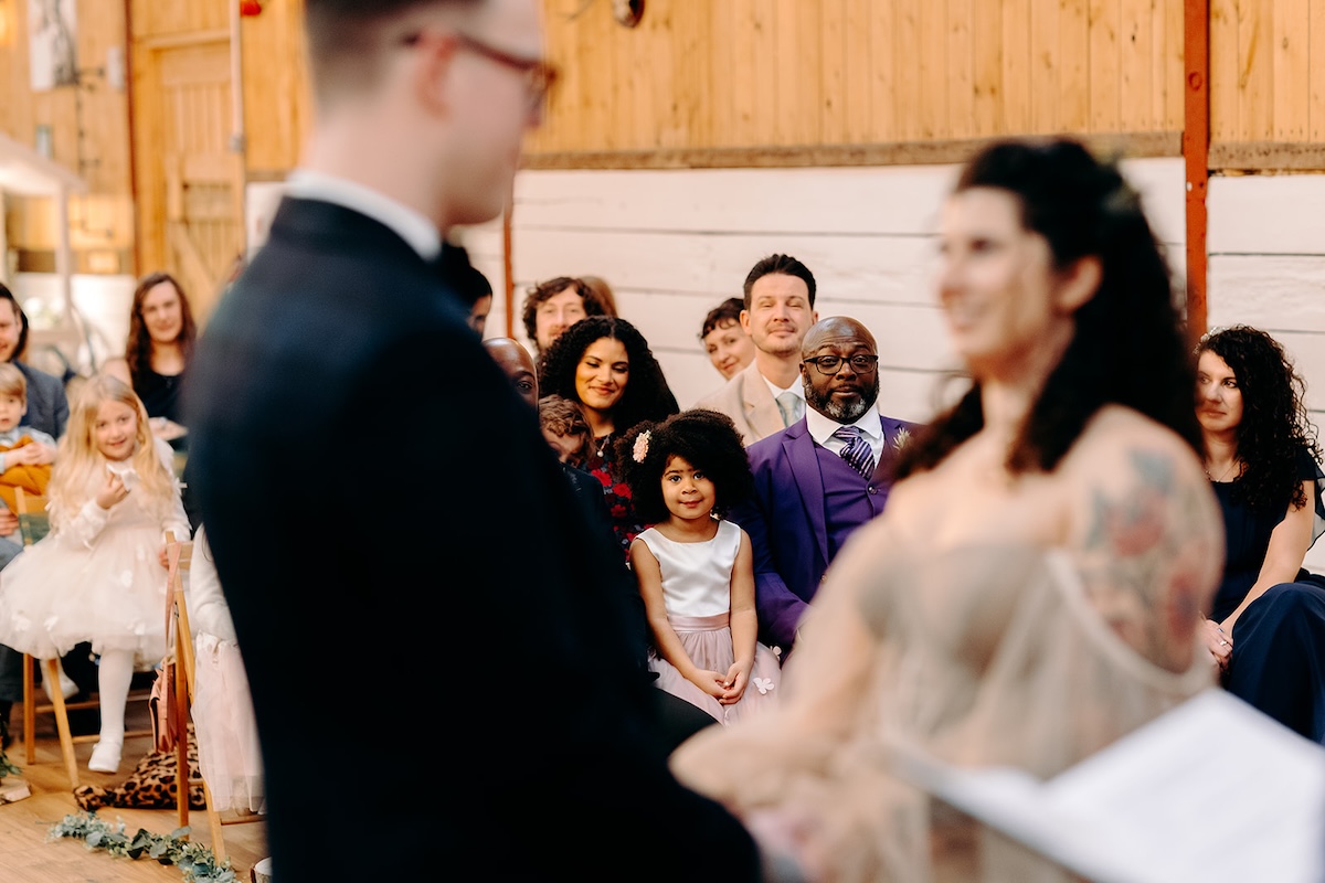 Couple holding hands during the ceremony at their February wedding at The Wellbeing Farm, photographed with natural documentary wedding photography.