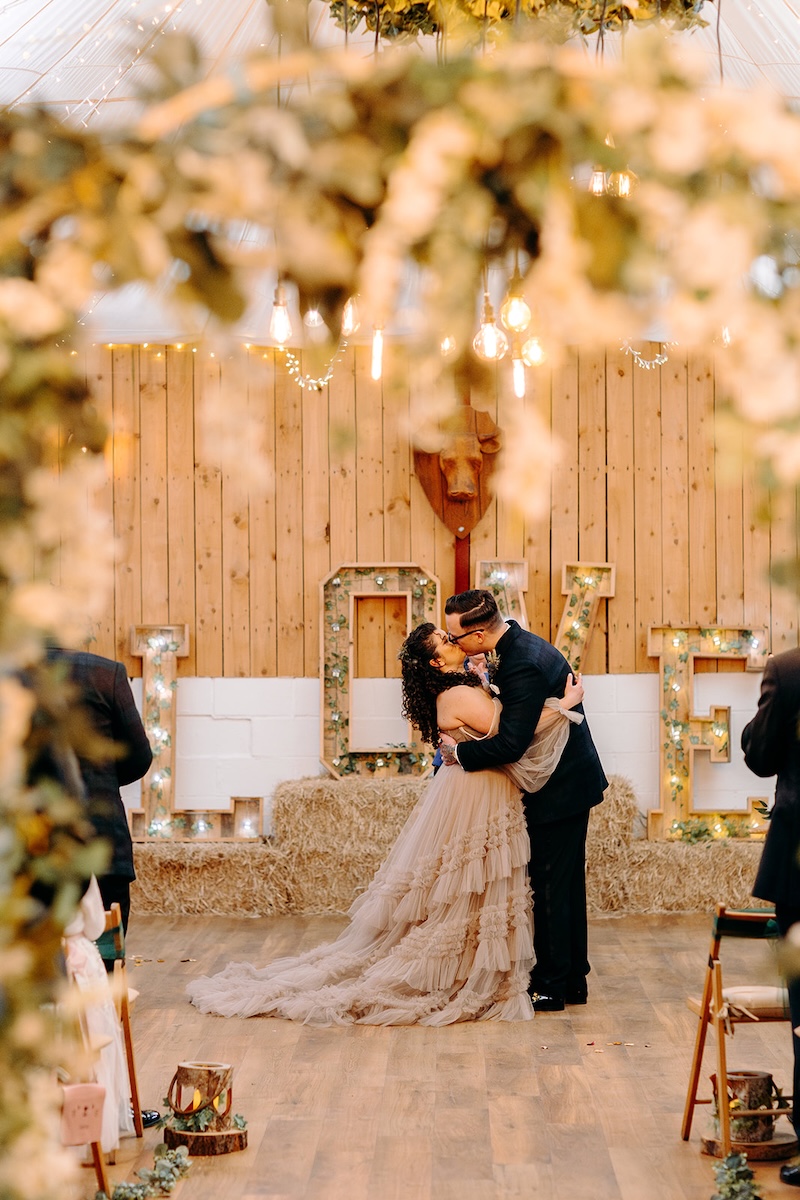 Couple smiling at each other while holding hands during their ceremony in the wooden barn.