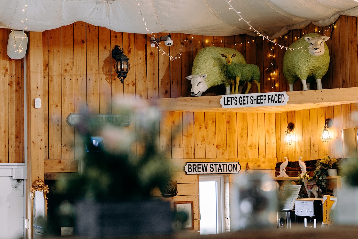 Wooden shelves with greenery and rustic décor inside the barn at The Wellbeing Farm wedding venue, captured with natural wedding photography.