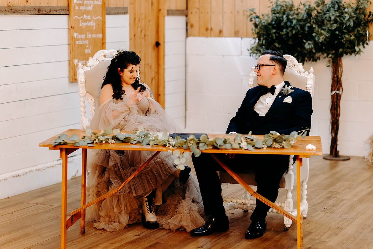 Couple chatting and smiling while completing the register during their relaxed winter wedding ceremony.