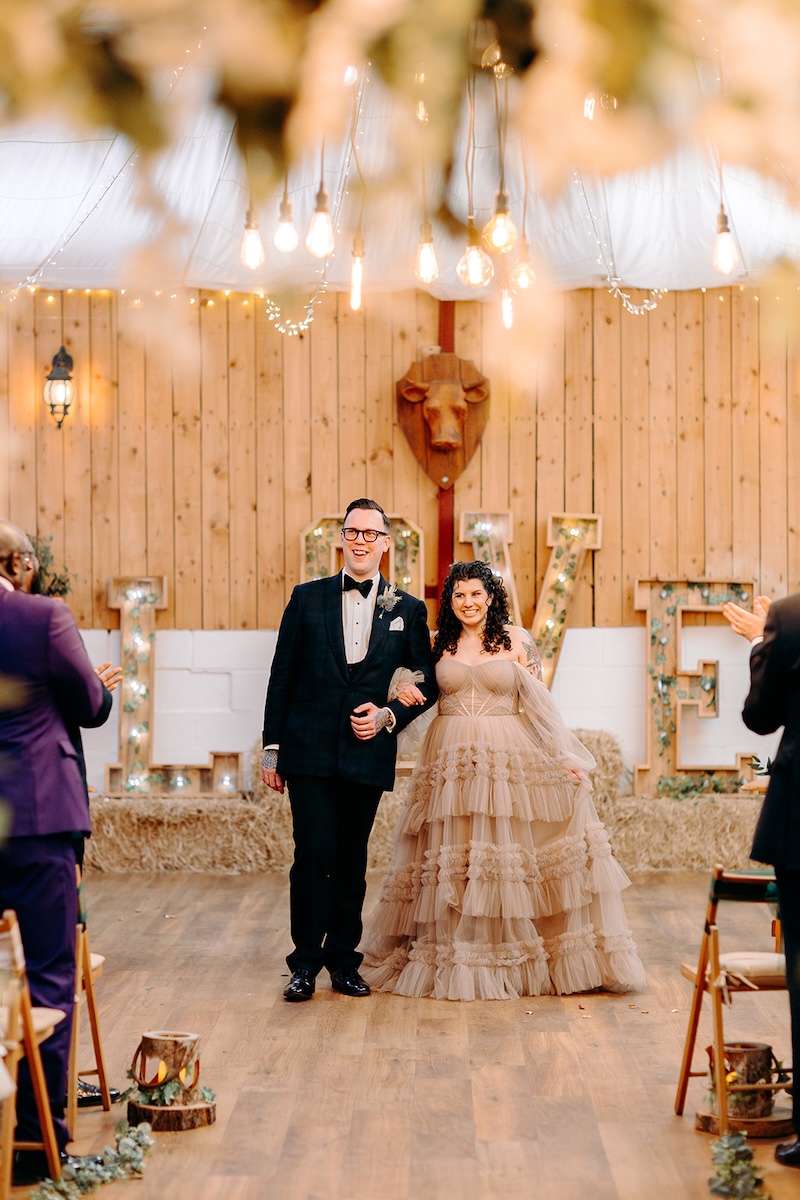Guests smiling and watching the couple during the ceremony inside The Wellbeing Farm barn.