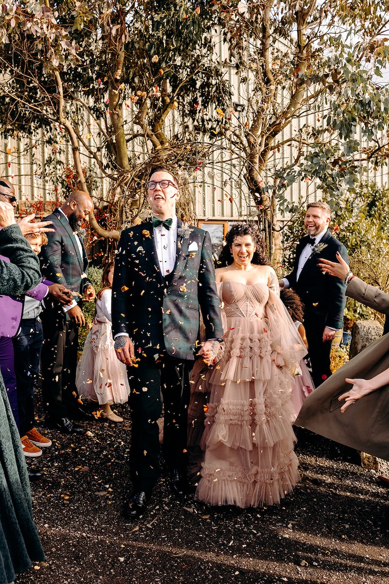 Guests throwing colourful confetti as the couple celebrate outside the venue courtyard.