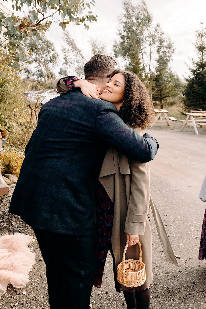 Wedding guests hugging and congratulating each other outside the barn after the ceremony.