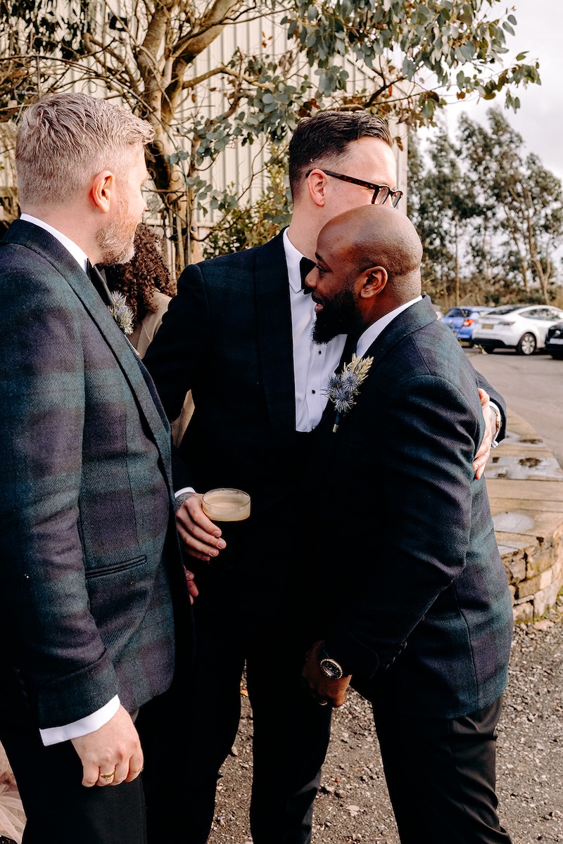Groom greeting friends during the winter wedding drinks reception, photographed in a relaxed documentary style.