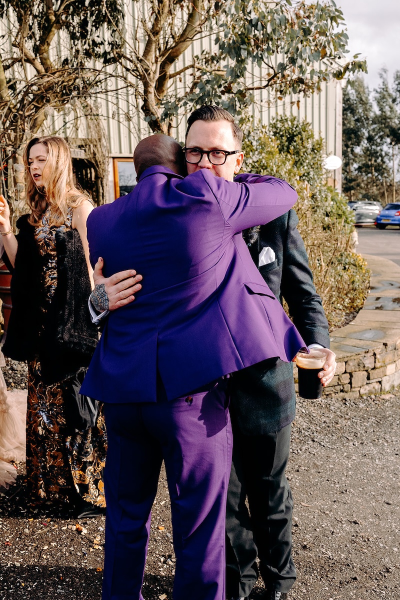 Guests hugging and congratulating the couple outside the barn following the ceremony.