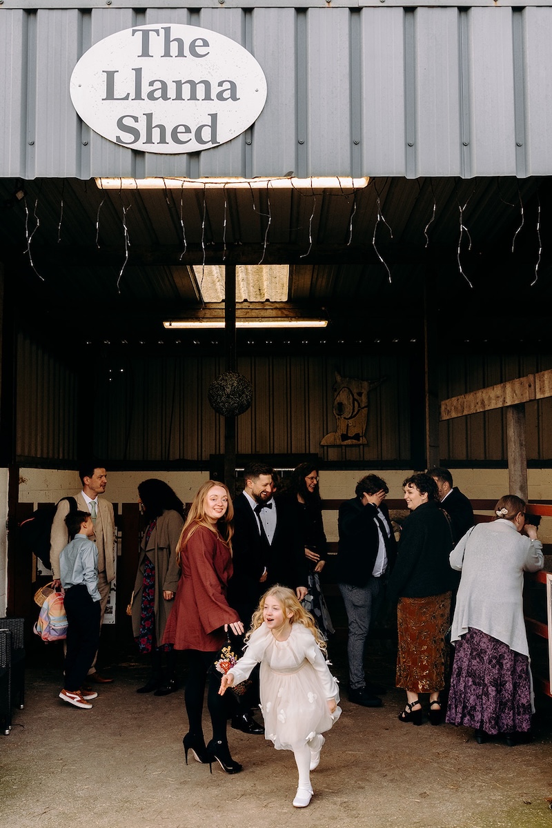 Guests walking towards the llama barn during the reception at The Wellbeing Farm wedding venue.
