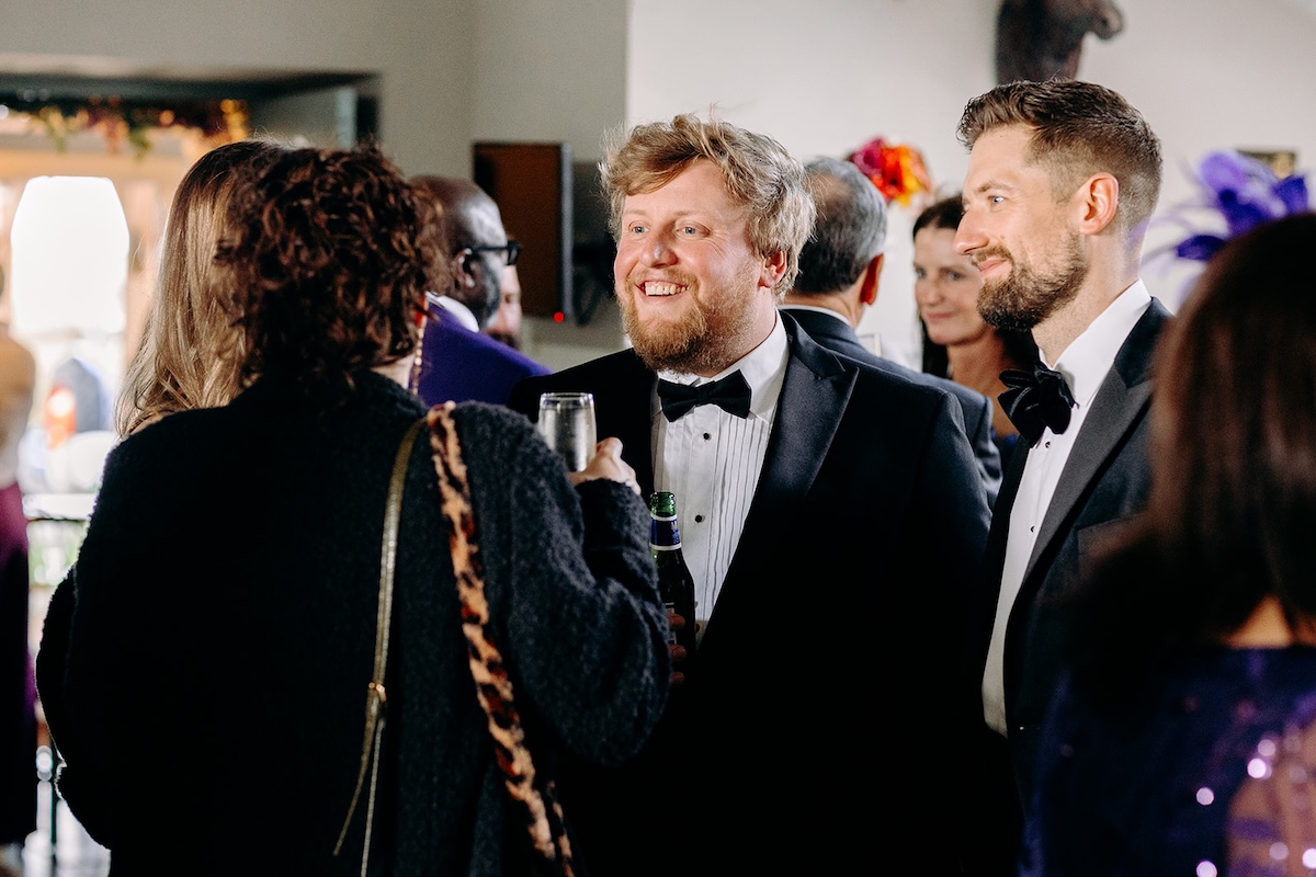 Groom chatting with friends during the drinks reception at The Wellbeing Farm wedding venue.