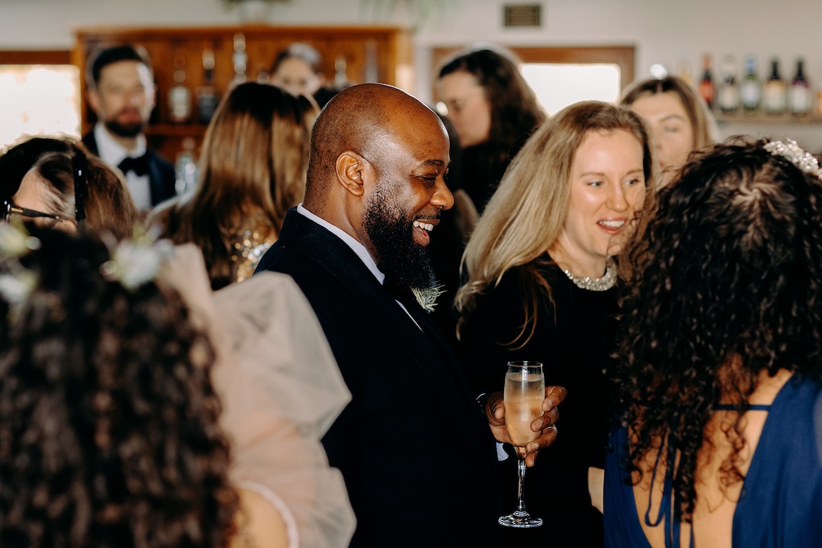 Guests chatting and holding drinks during the relaxed winter wedding reception.