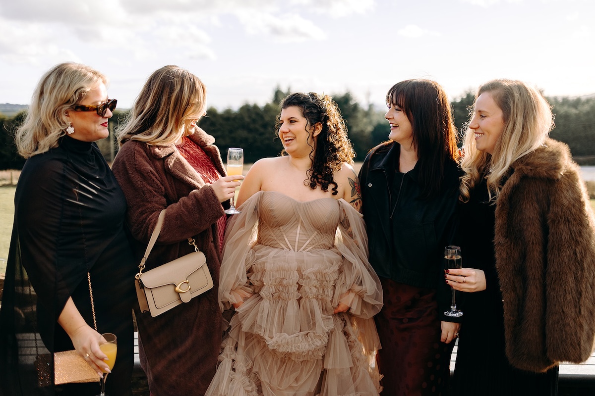 Bride chatting with guests beside the llama barn during the reception.