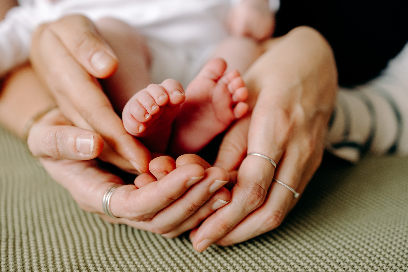 Parents holding newborn hands during cosy lifestyle family session