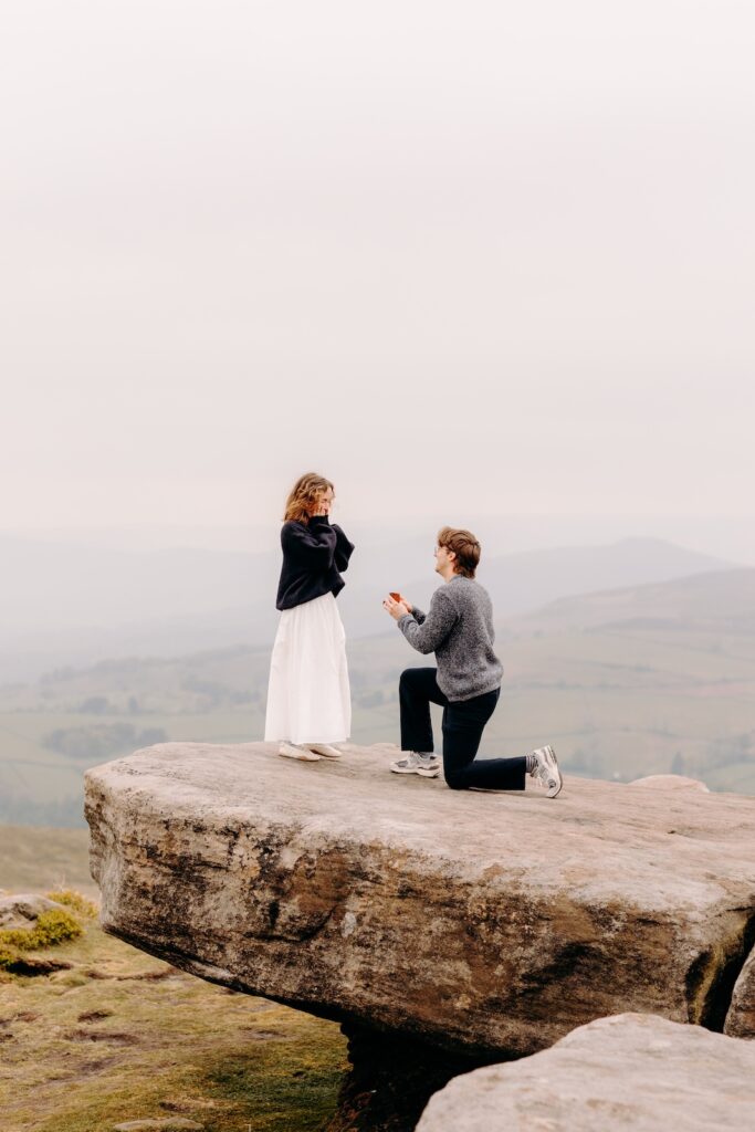 Couple embracing on cliff edge during romantic Derbyshire proposal photography