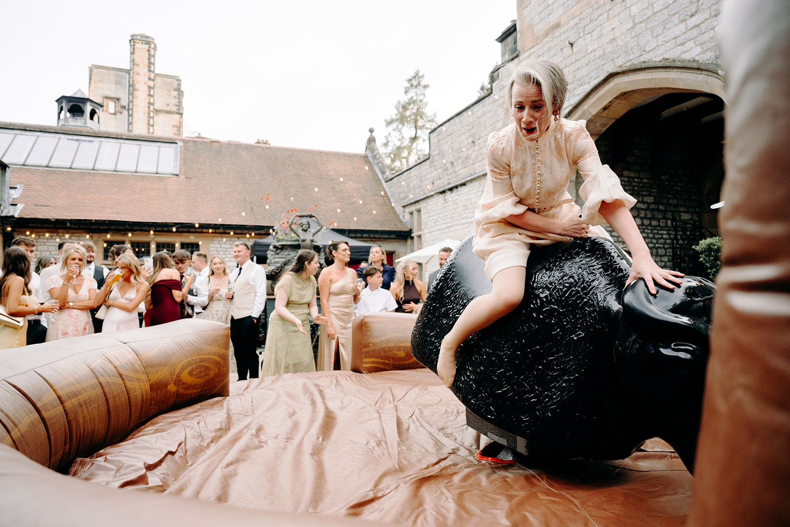 Guests laughing and watching the bucking bronco at this fun Derbyshire wedding.