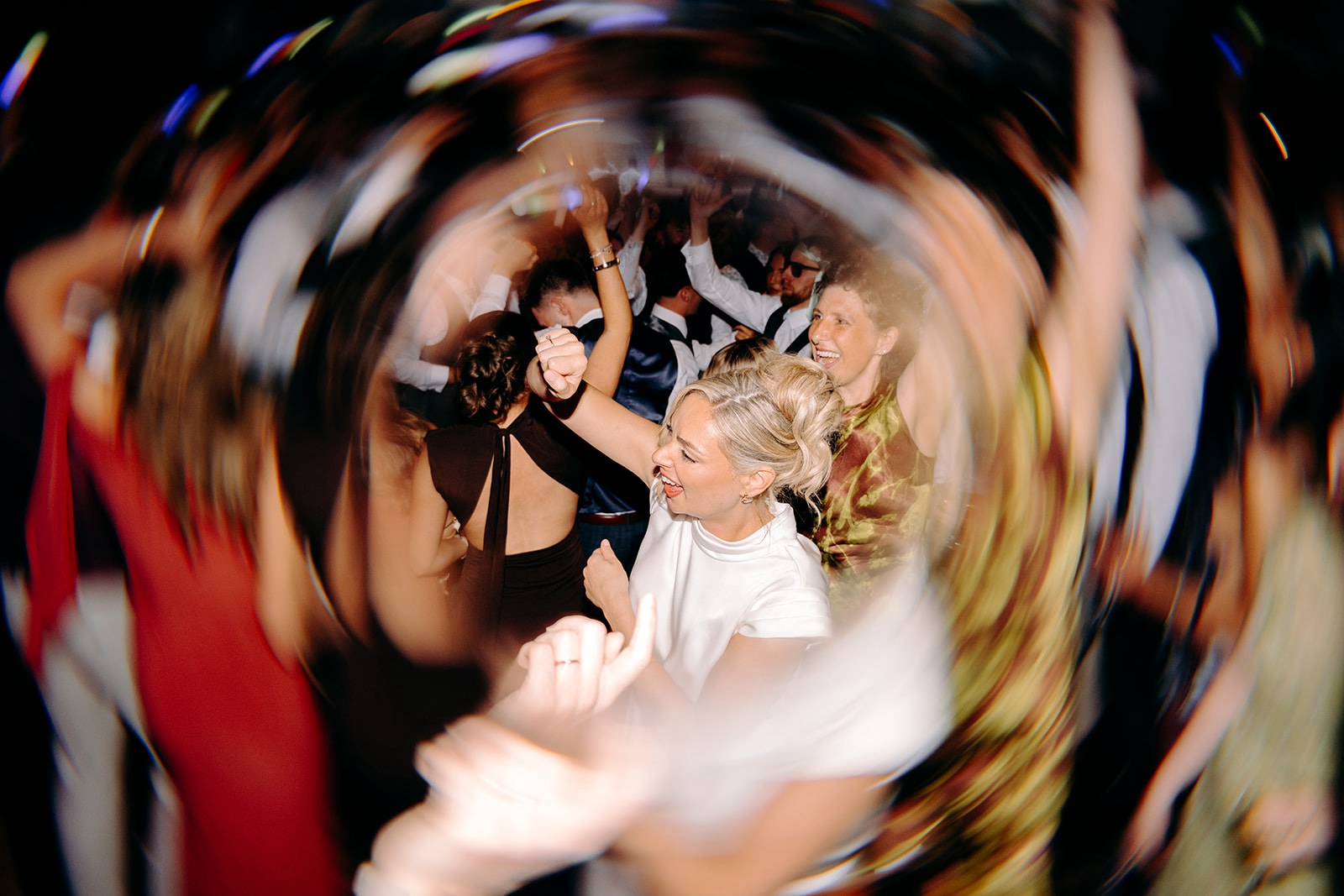 Friends dancing and laughing together during the late-night wedding party.