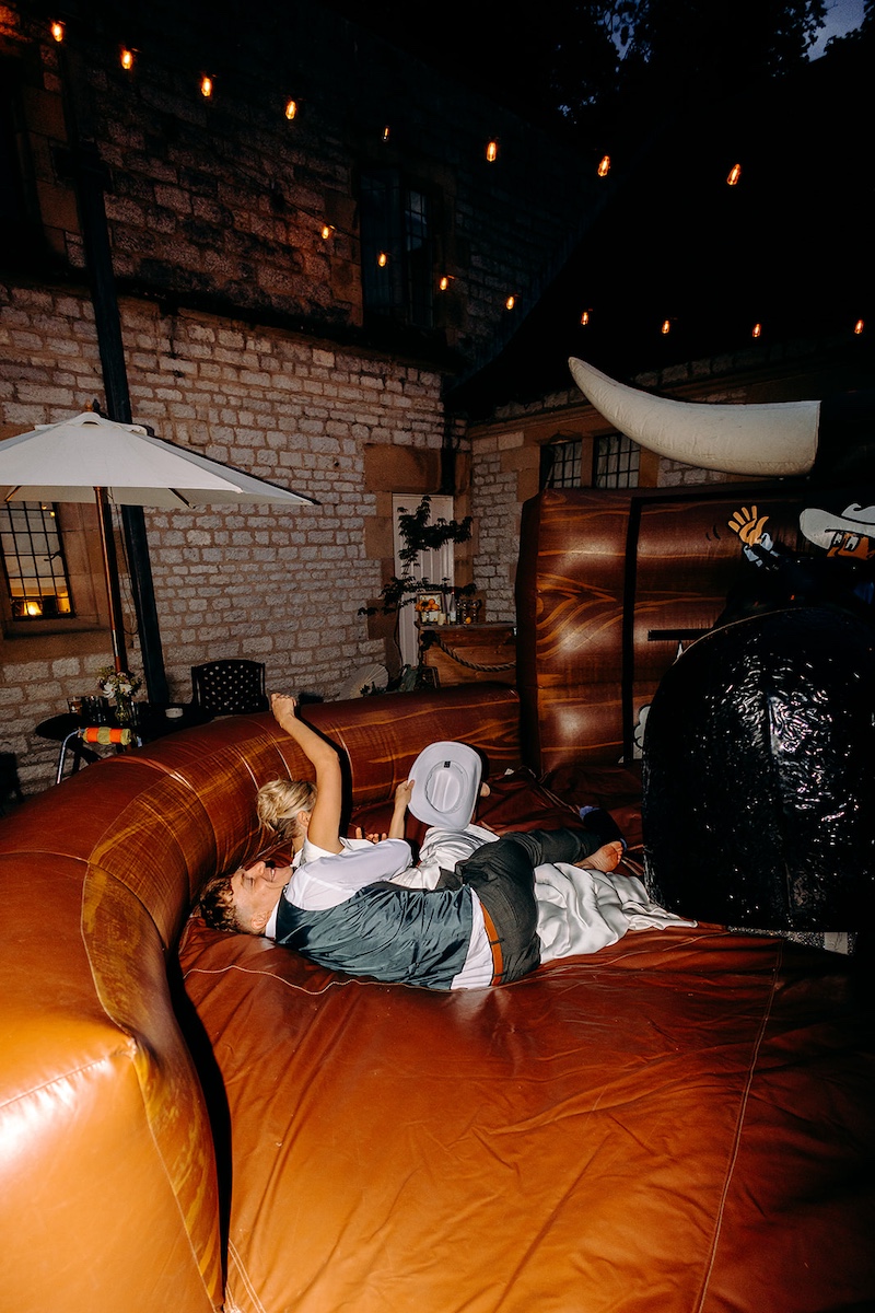 Groom lying on the inflatable bucking bronco after a night of wedding celebrations.