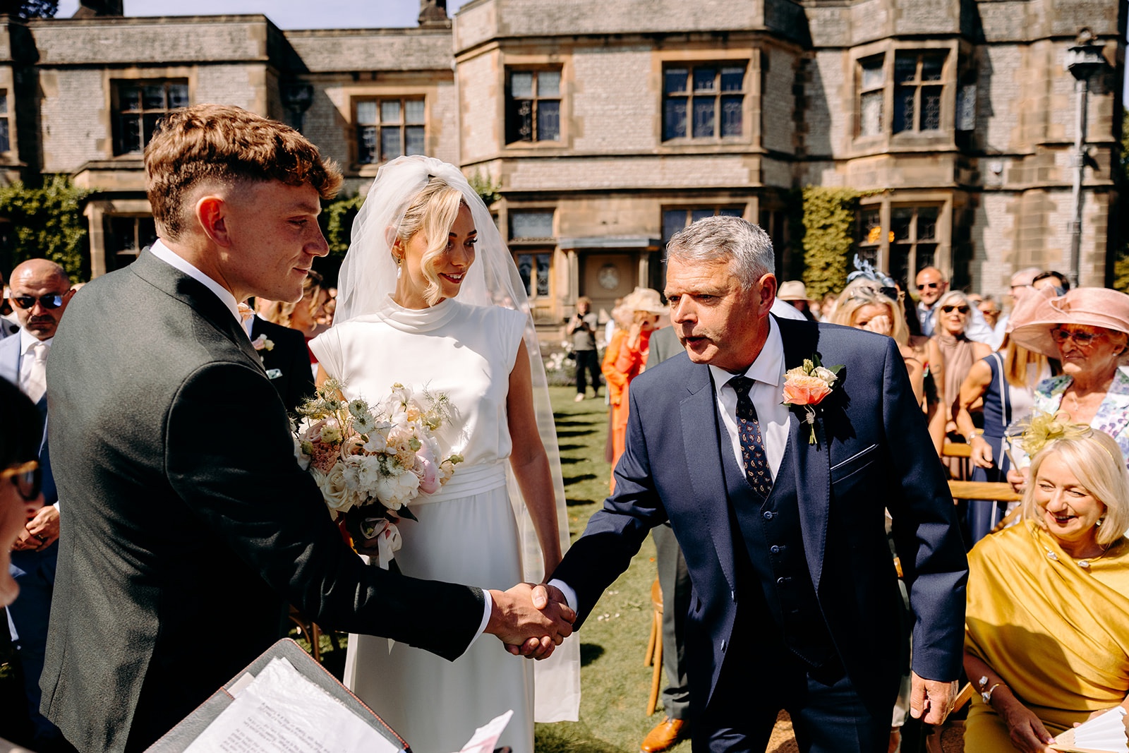 Hands held during an outdoor wedding ceremony in the gardens at Thornbridge Hall.