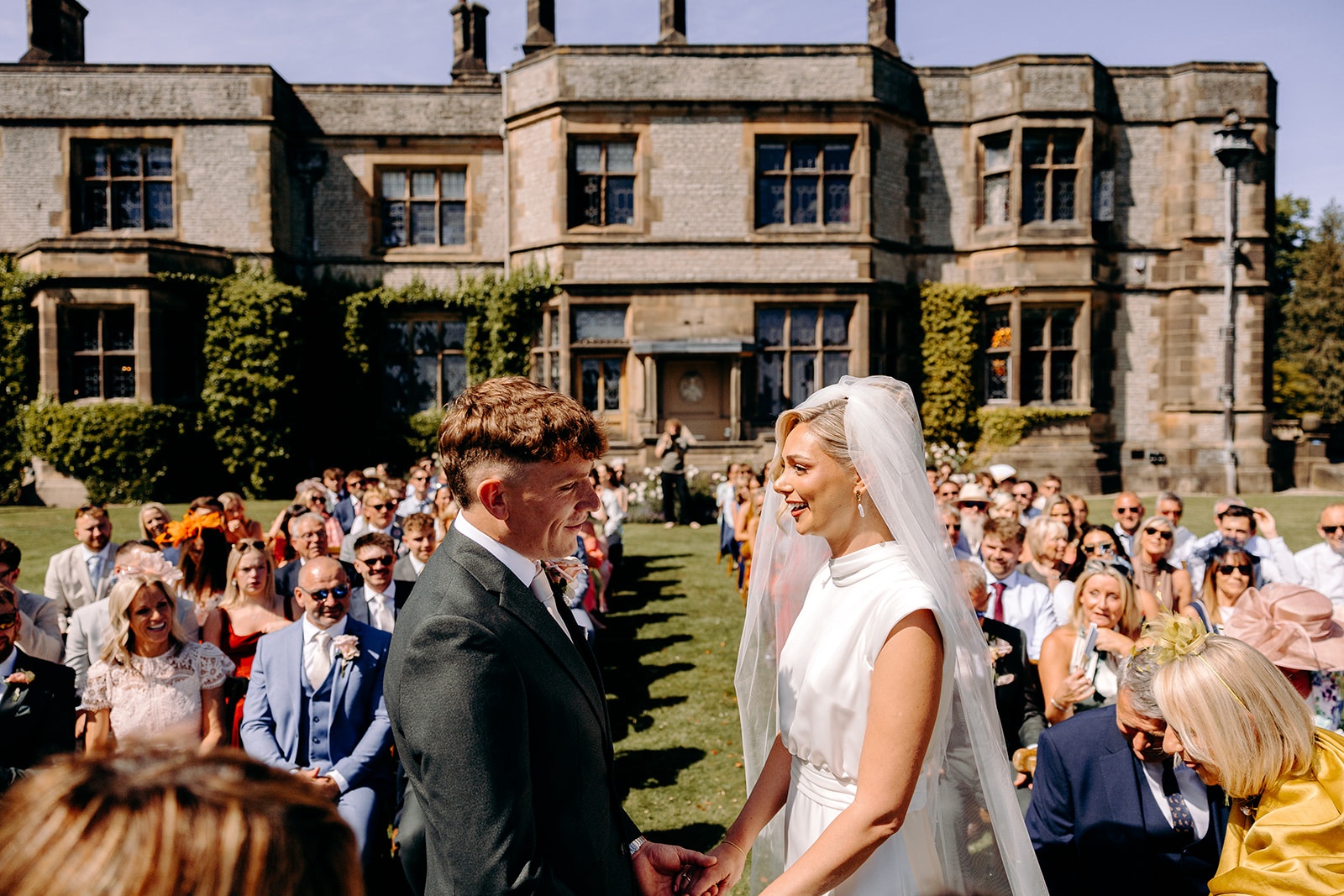 Bride and groom smiling at each other during their Peak District wedding ceremony.