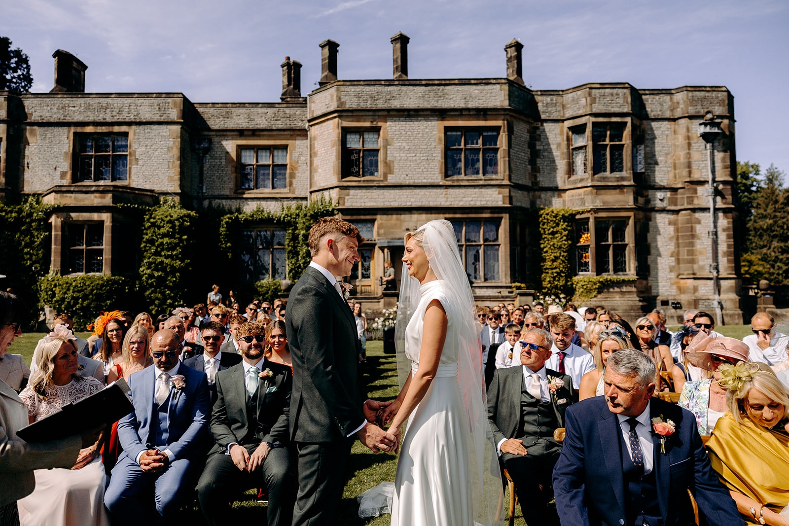 Wedding vows exchanged during a sunny outdoor ceremony, captured by a Thornbridge Hall wedding photographer.