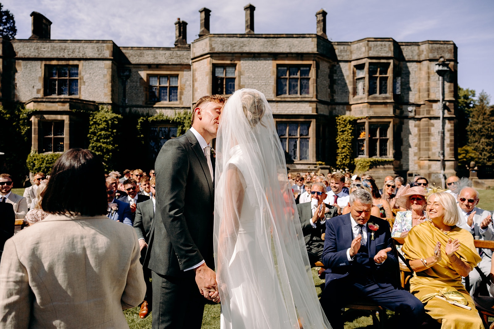 First kiss during an outdoor wedding ceremony at Thornbridge Hall in the Peak District.