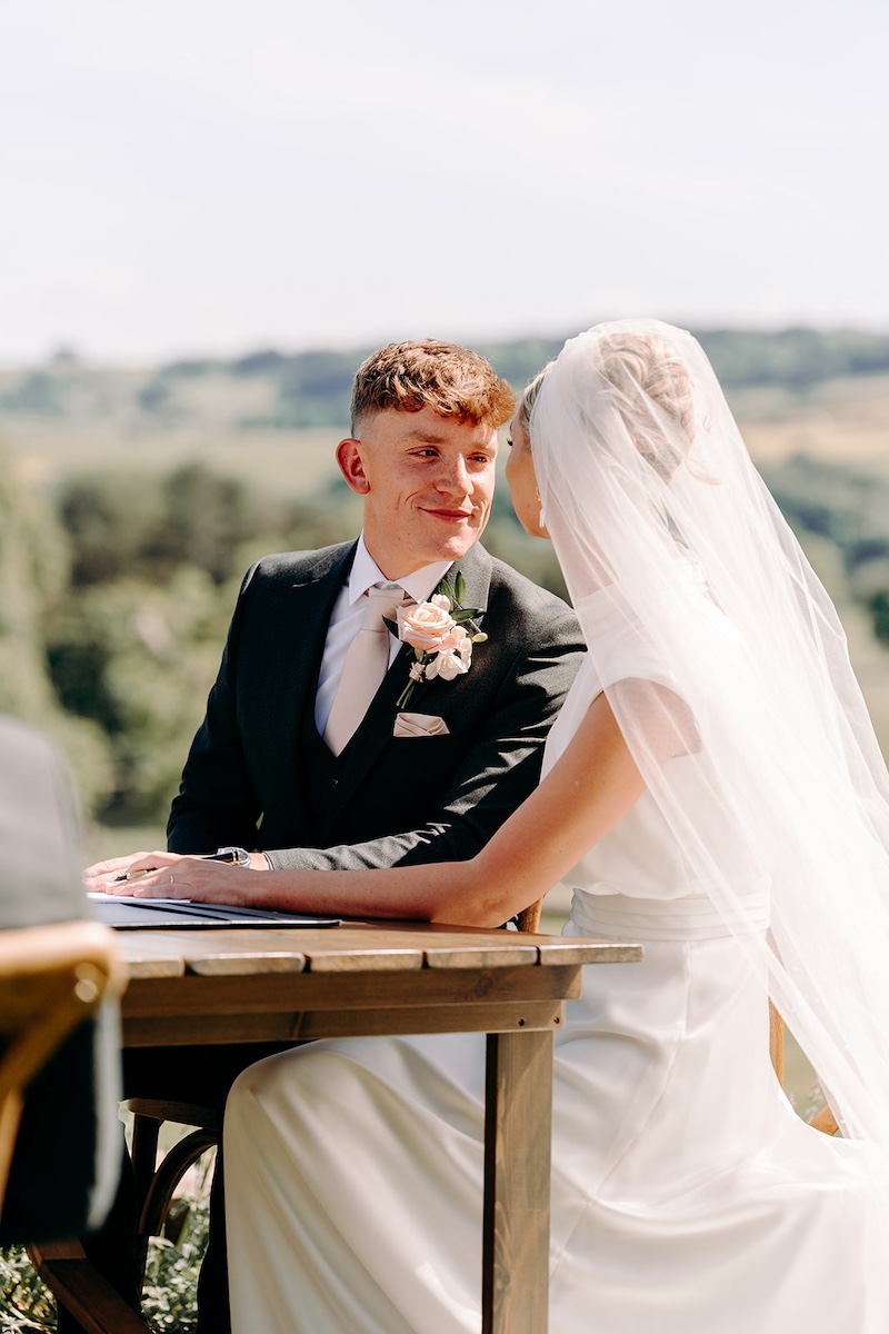 Wedding register being signed in the sunshine at Thornbridge Hall.