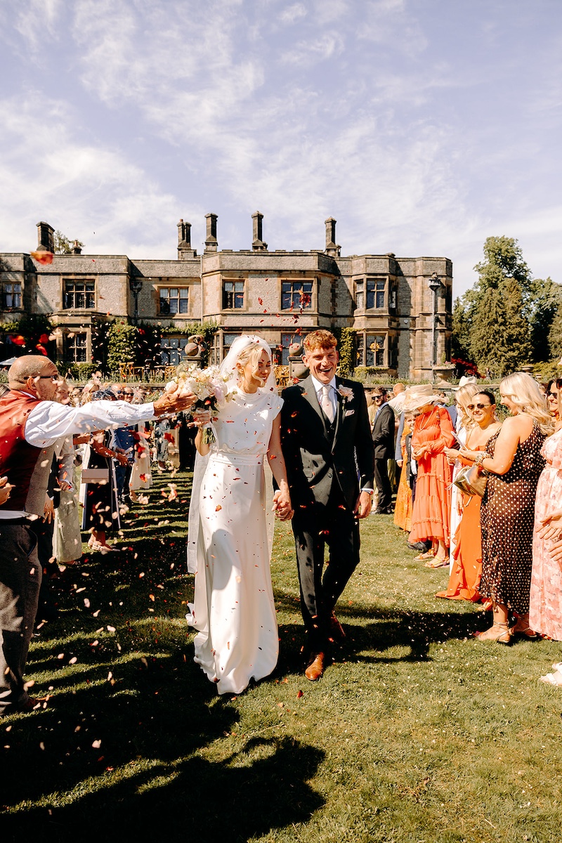 Bride and groom celebrating as they walk back down the aisle at Thornbridge Hall.