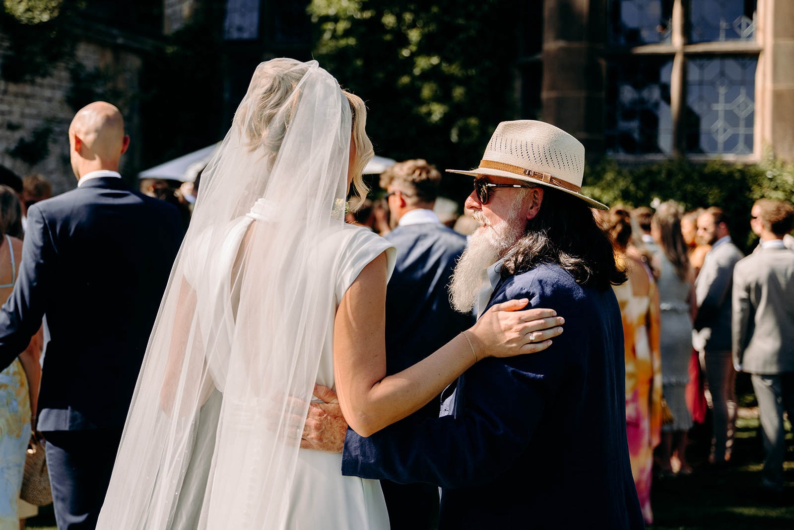 Bride greeting a wedding guest in the sunshine after the ceremony.