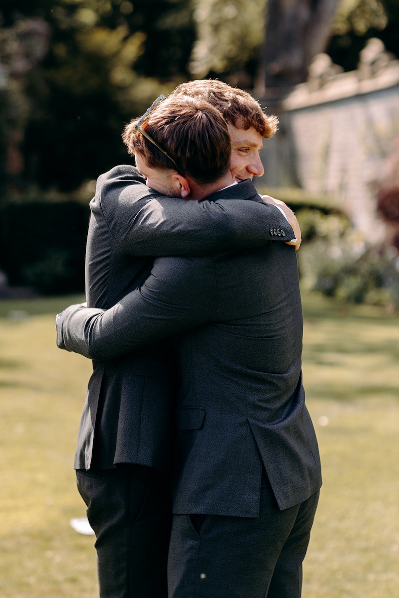 Groom hugging a wedding guest during the relaxed afternoon celebrations.