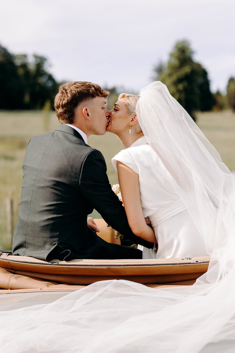Just-married kiss in the back of a vintage Rolls Royce during a Thornbridge Hall wedding.